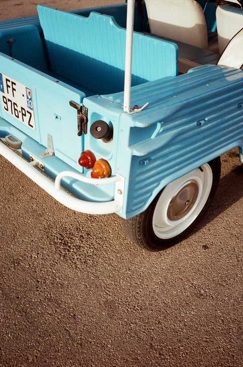 Small blue toy truck on a dirt surface