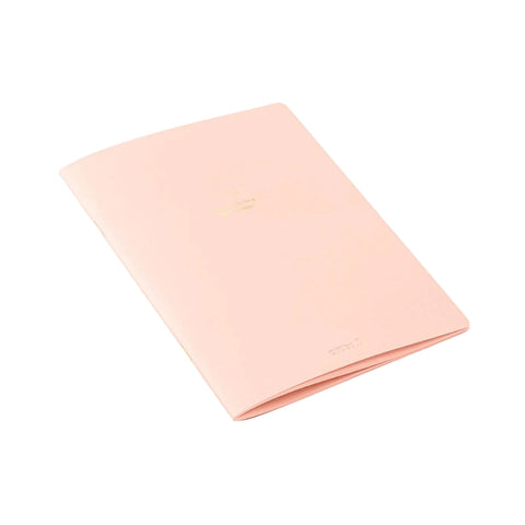 A peach pink notebook with gold foil text on the cover, photographed at an angle on a clean white background.