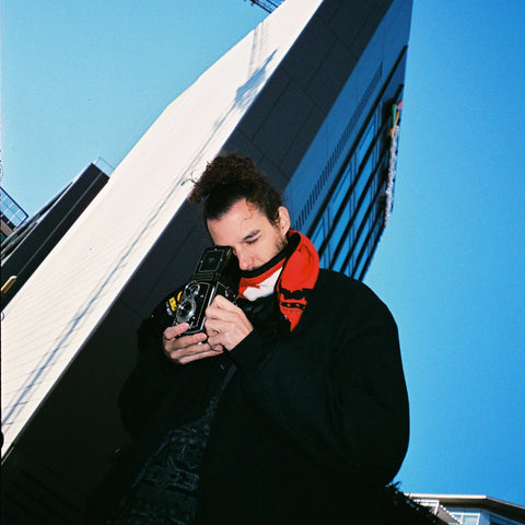Person holding a vintage camera against a modern building with a crane in the background