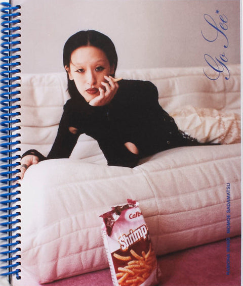 Notebook with a photo of a person on a couch and a snack packet on a white background