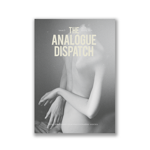 A rectangular art print or poster centered on a white background, featuring a grayscale photograph of a nude human figure with the title text 'THE ANALOGUE DISPATCH' in pale cream lettering near the top.