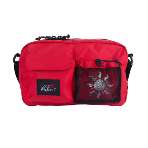 A red crossbody bag with a front pocket, a black mesh pocket featuring a white sun graphic, and a black brand patch that reads 'Long Weekend'.