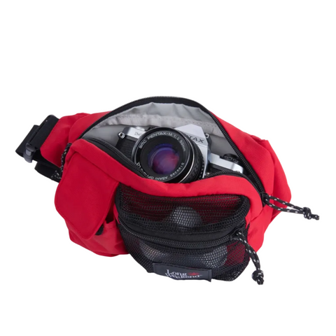 A red camera bag with a black mesh front pocket, shown open with a camera inside, on a light gray background.