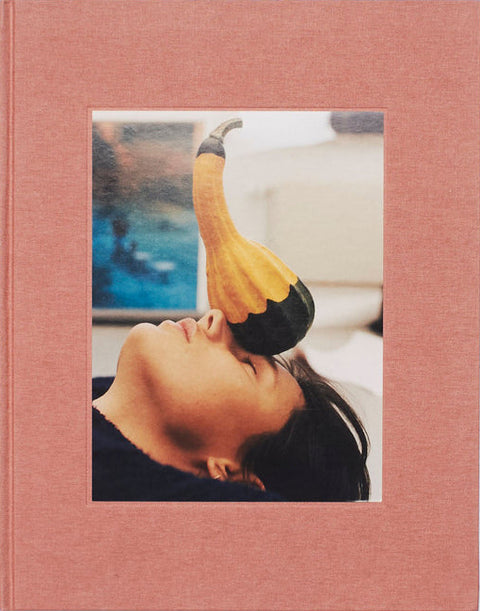 Pink photo album with a cutout of a person with a yellow bird on their head against a scenic background.